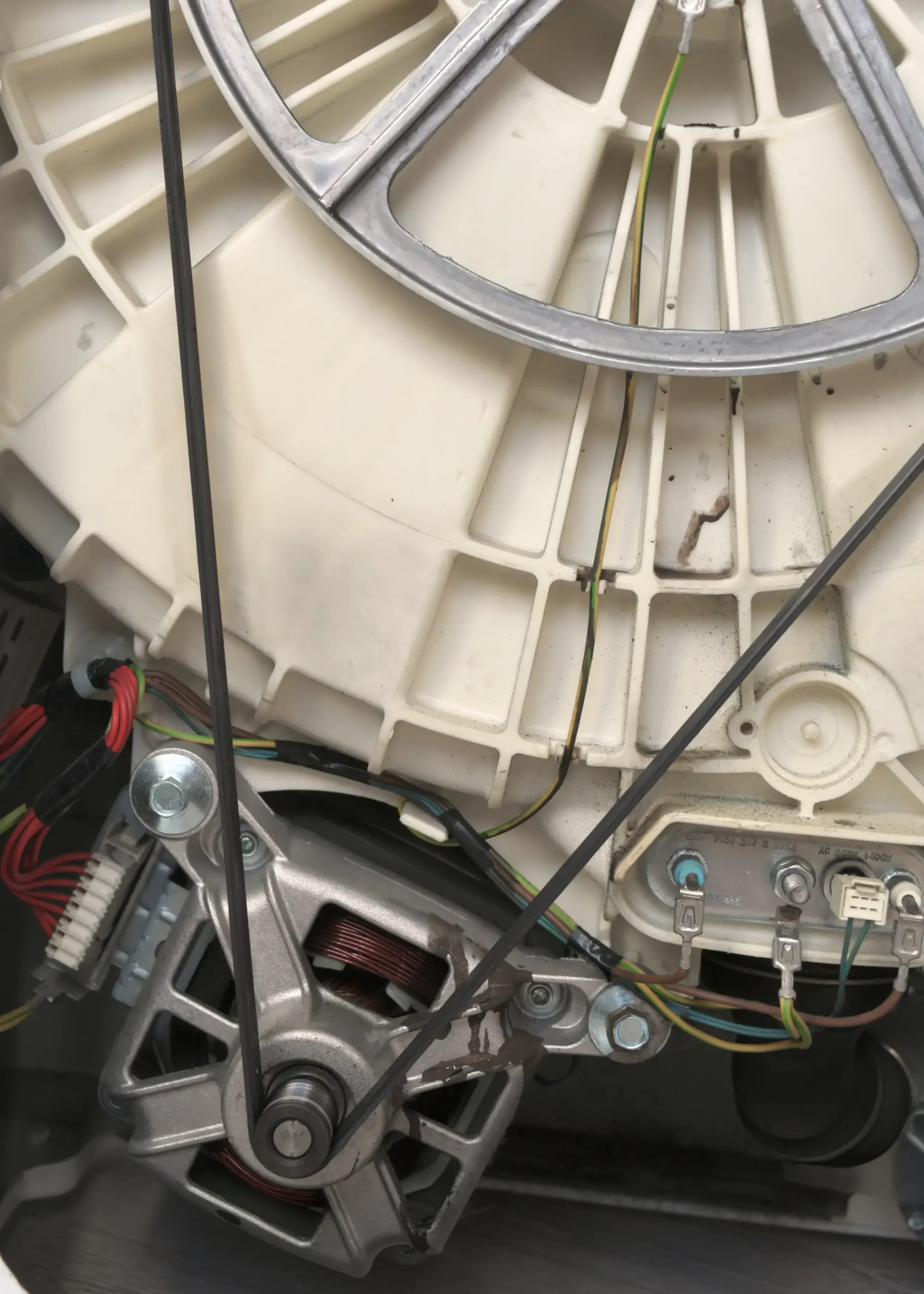 Close-up of a washing machine motor and pulley system with wires