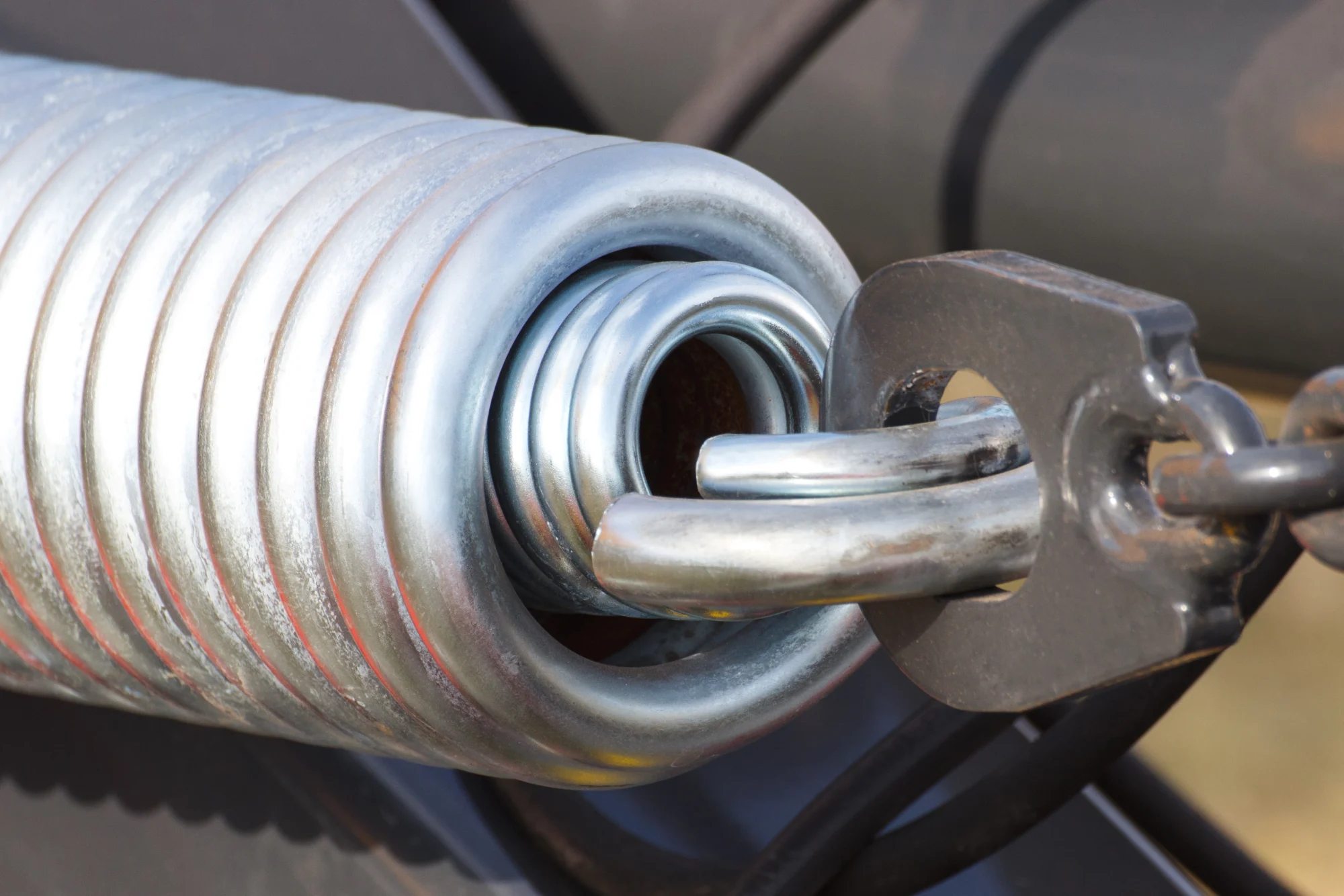 Close-up of a large metal spring connected to a chain link.