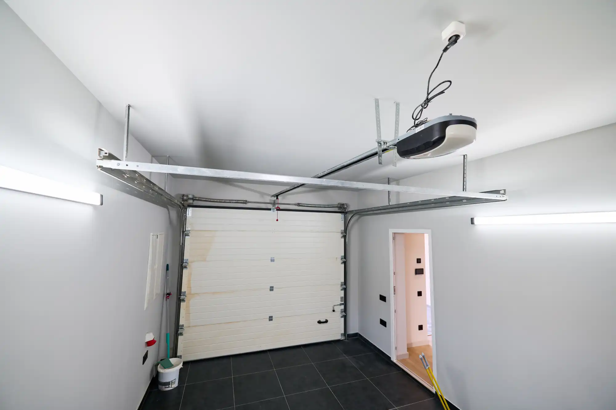 Interior view of a garage with a white sectional door and opener.