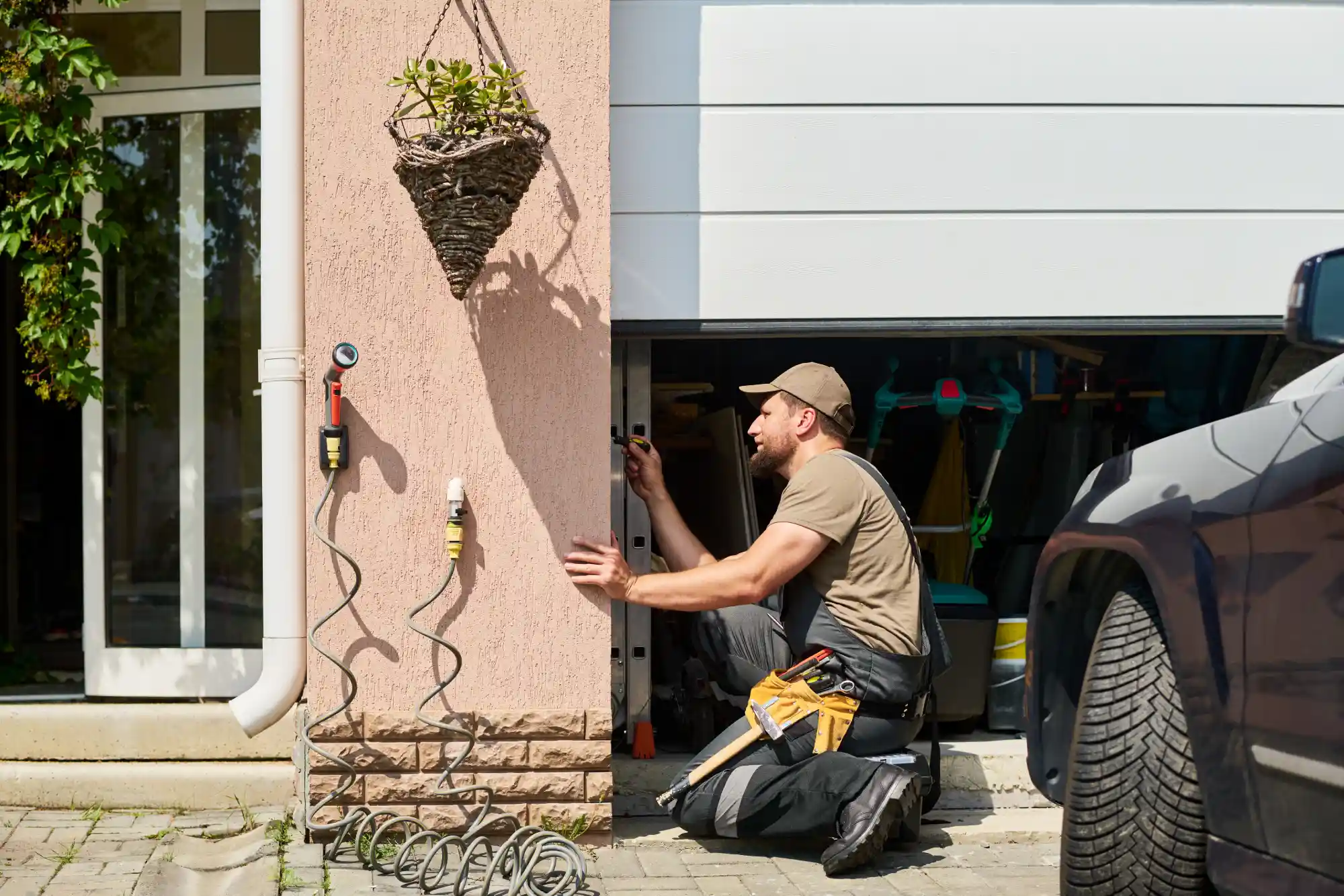 Man repairing a garage door opener mechanism on a sunny day