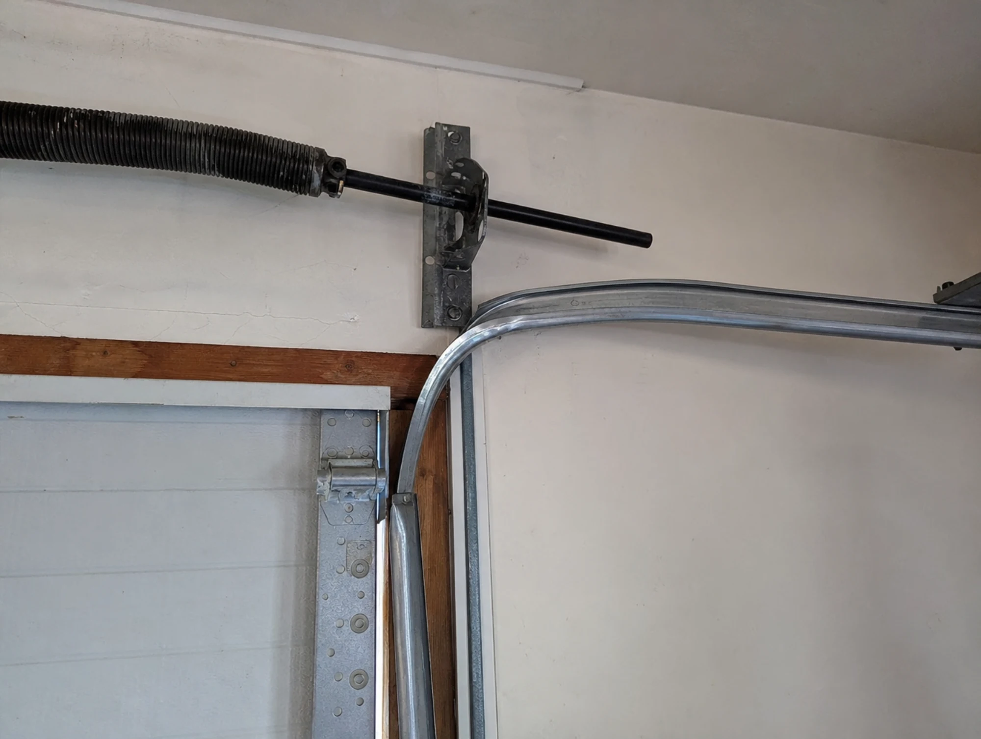 Close-up of a garage door torsion spring system and curved track.